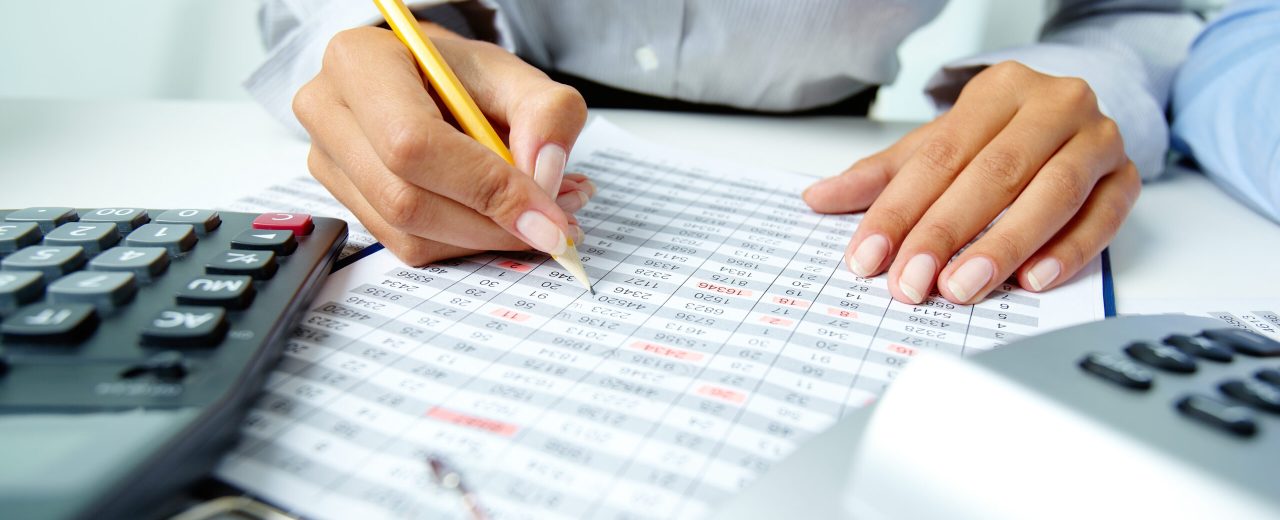 Photo of human hands holding pencil and ticking data in documents